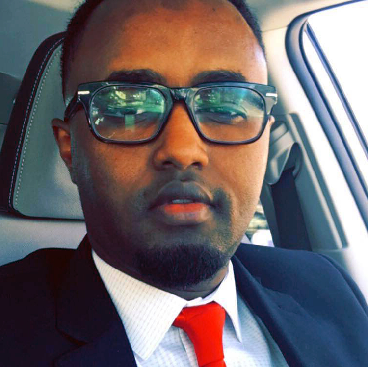 A Somali man dressed in a suit sits in his car.