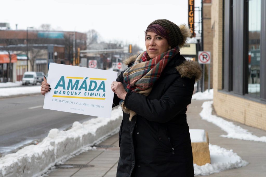Amáda Márquez Simula waves a rally sign to street traffic on a cold winter day.