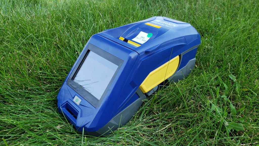 A portable label printer sitting on green grass.