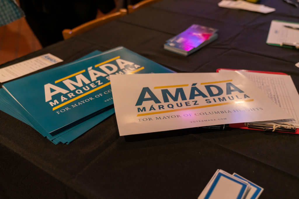 Political campaign pledge cards, palm cards, and rally posters that read Amáda Márquez Simula for Mayor of Columbia Heights.
