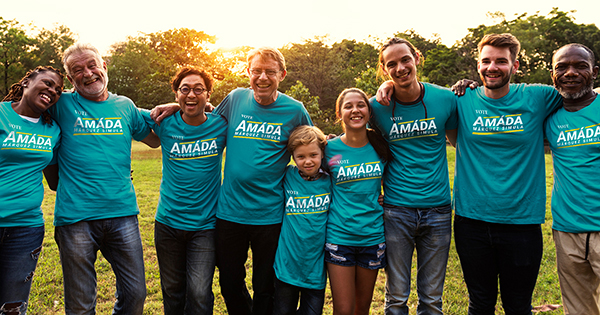 A group of mixed-race volunteers wearing teal T-shirts for Amáda Márquez Simula post for a photo at sunsuet.