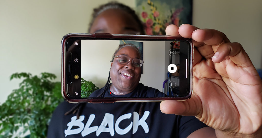 A black woman takes a selfie video, recording a testimonial about why she is voting for Amáda Márquez Simula.